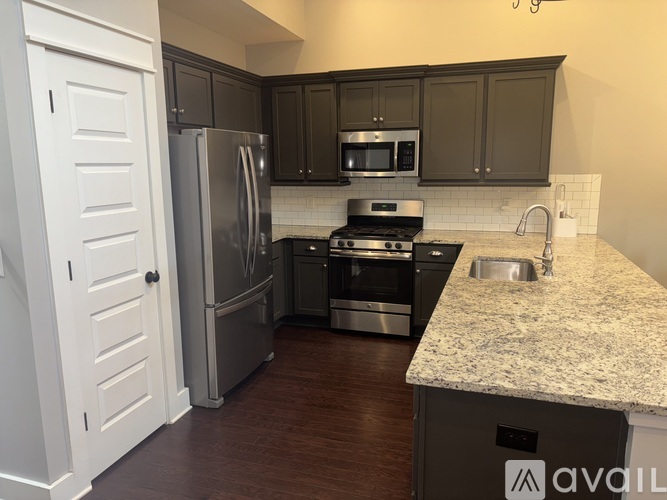 A kitchen with a refrigerator, oven, microwave, and sink.