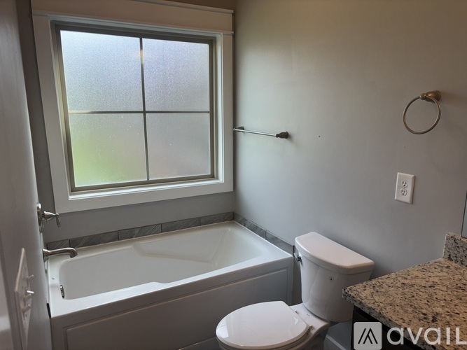 A bathroom with a tub, toilet, and window.