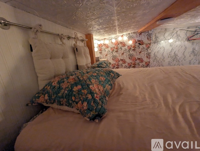 A bed with a floral pillow and a wall with a floral wallpaper.