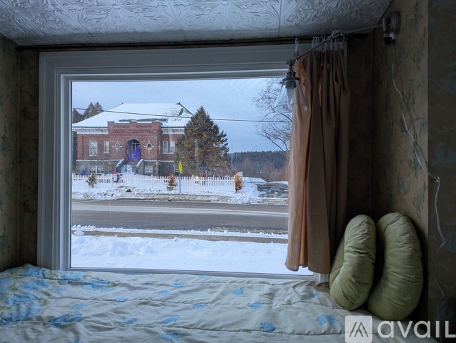A bedroom with a view of a snowy street and a red building.