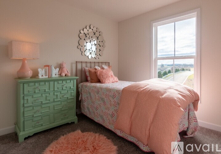 A bedroom with a green dresser and a pink bedspread.