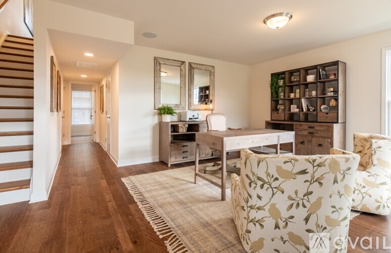A spacious living room with a staircase on the left and a couch with a floral pattern on the right.