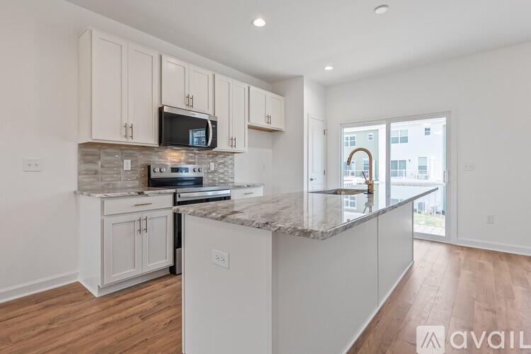 A kitchen with white cabinets and a marble countertop.