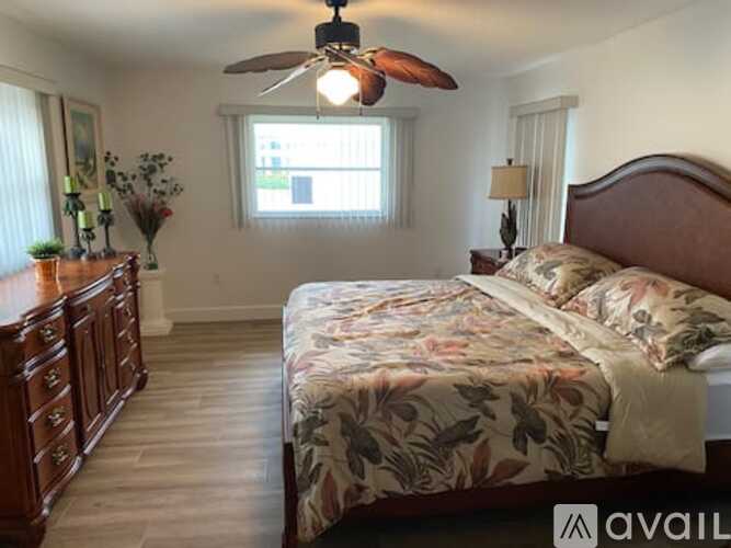 A bedroom with a bed, dresser, and ceiling fan.
