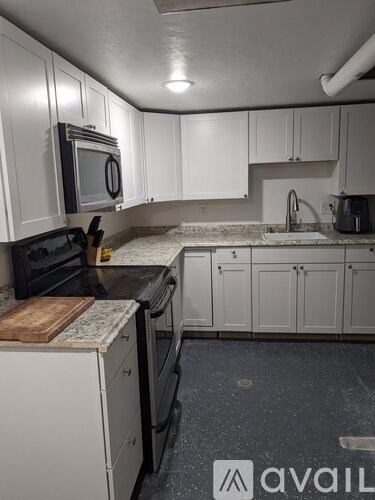 A kitchen with white cabinets and black appliances.