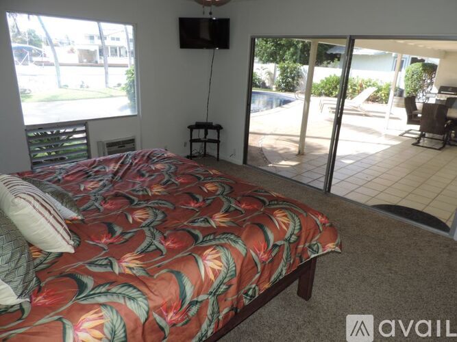 A bedroom with a bed, a television, and a sliding glass door leading to a patio.