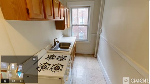 A kitchen with a stove, sink, and cabinets.