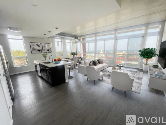 A modern living room with a kitchen area and a view of the city.