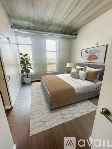 A bedroom with a large bed and a plant in a white pot.
