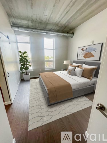 A bedroom with a large bed and a plant in a white pot.