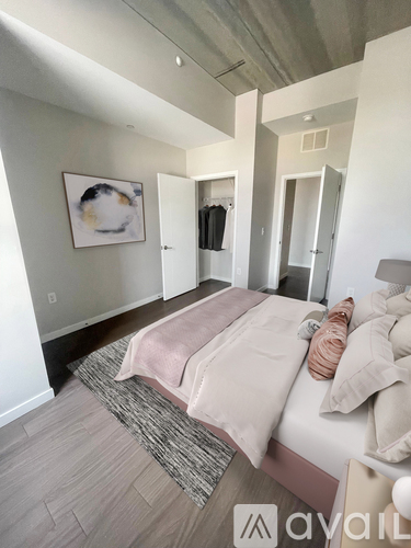 A bedroom with a bed, pillows, and a painting on the wall.