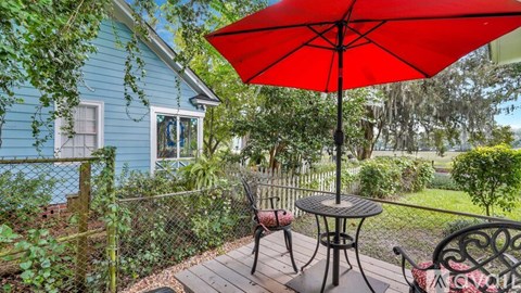 A red umbrella is on a table outside a house.
