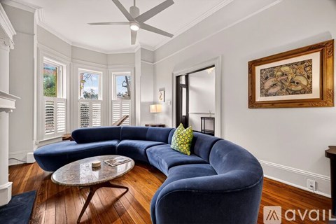 A living room with a blue couch and a ceiling fan.