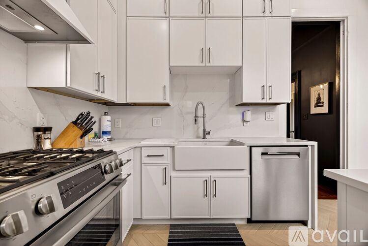A modern kitchen with white cabinets and stainless steel appliances.