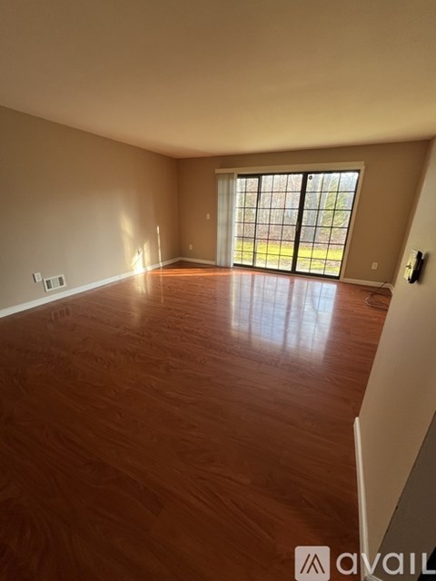 A room with wooden flooring and a sliding glass door.
