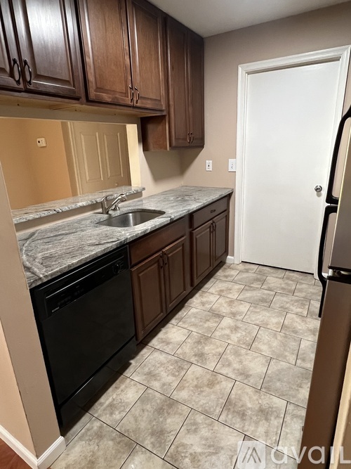 A kitchen with a black dishwasher and a white door.