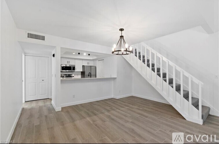 A white interior space with a staircase and a chandelier.