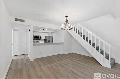 A white interior space with a staircase and a chandelier.
