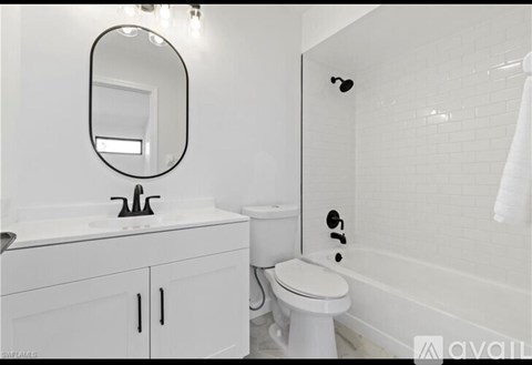A white bathroom with a toilet, sink, and mirror.