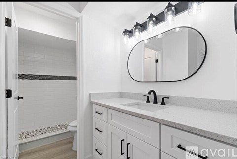 A bathroom with a white sink and a round mirror.