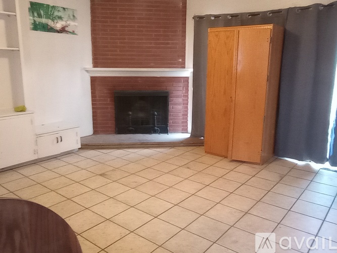 A room with a fireplace and a wooden cabinet.