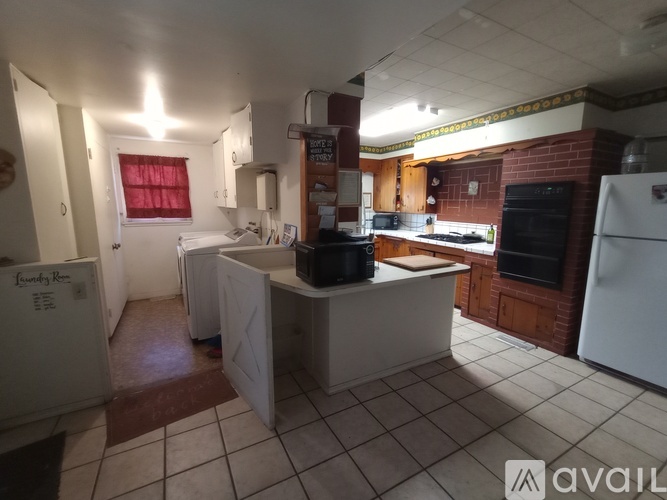 A kitchen with a white fridge, black stove, and white island.