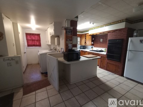 A kitchen with a white fridge, black stove, and white island.