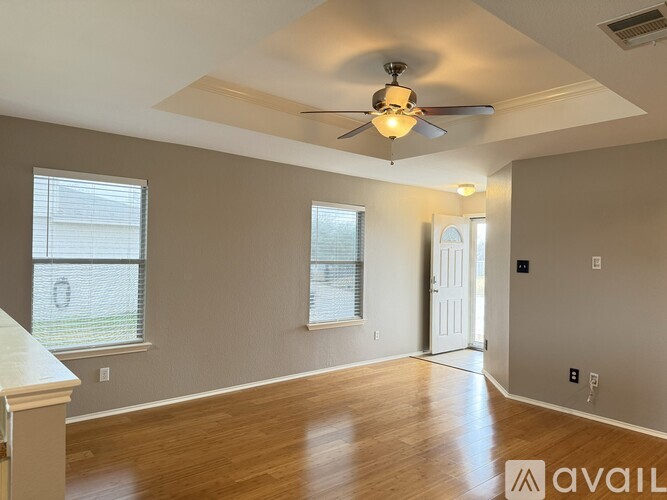 A spacious room with a ceiling fan and wooden flooring.