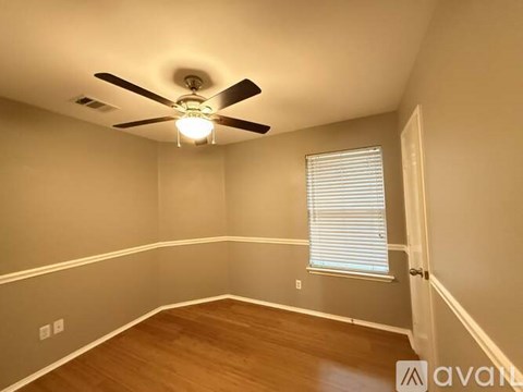 A spacious room with a ceiling fan and wooden flooring.