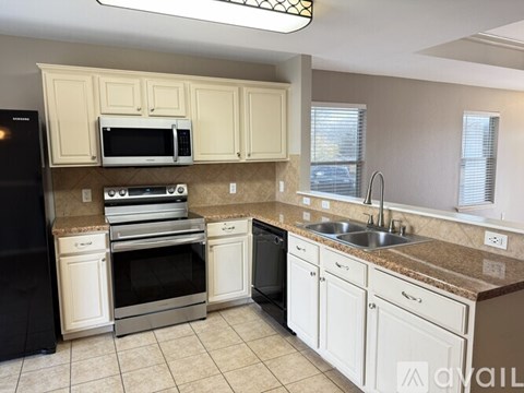 A kitchen with white cabinets and a black refrigerator.
