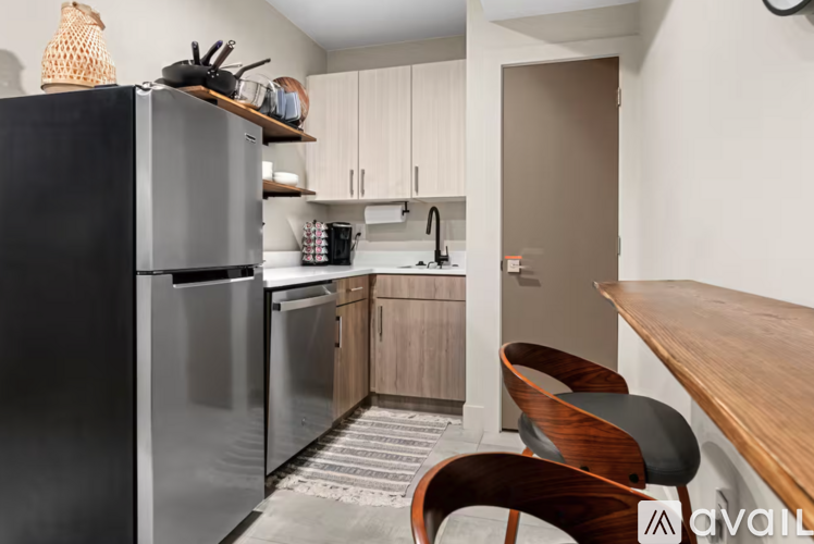 A kitchen with a black refrigerator and wooden chairs.