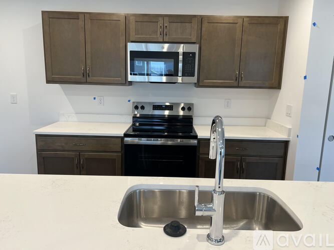 A kitchen with a sink, stove, and microwave.