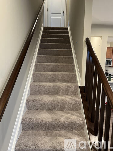A staircase with a beige carpeted runner and wooden balusters.