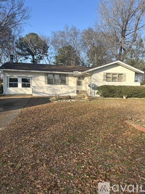 A house with a lawn covered in leaves in front of it.