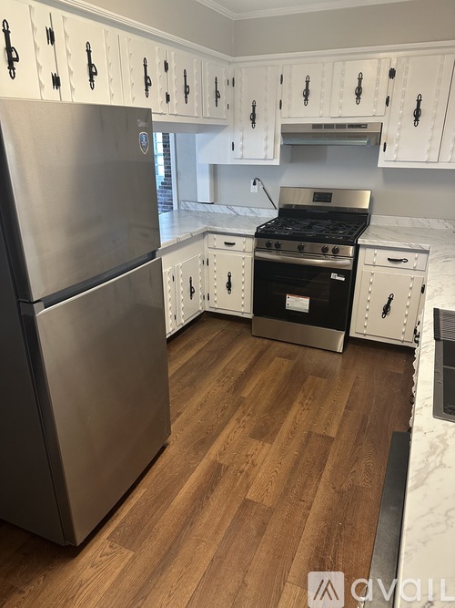 A kitchen with a stainless steel refrigerator and wooden floors.