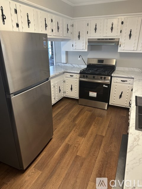 A kitchen with a stainless steel refrigerator and wooden floors.