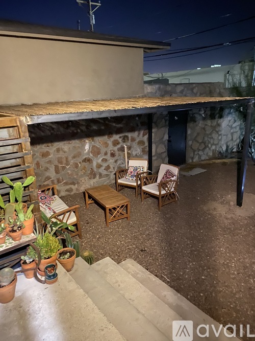 A patio area with a table, chairs, and potted plants.