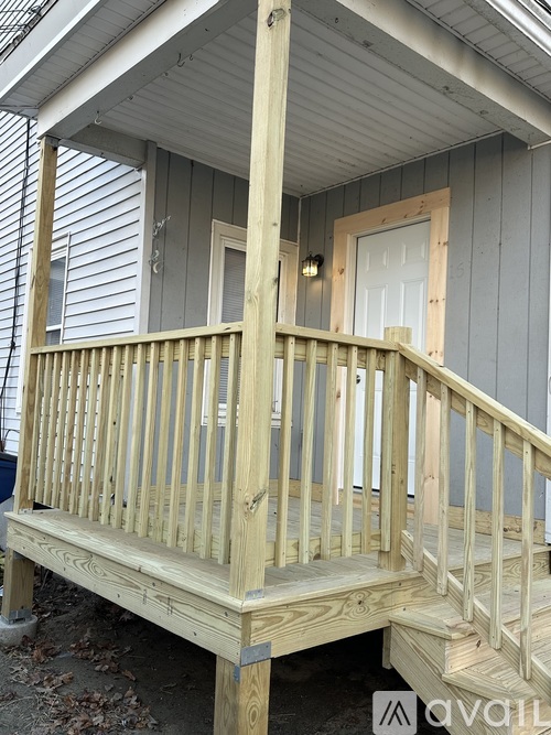 A wooden deck with a bench and a door is in front of a house.