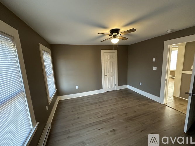 A room with a ceiling fan and wooden flooring.