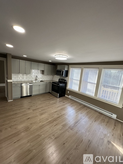 A spacious kitchen with wooden flooring and modern appliances.