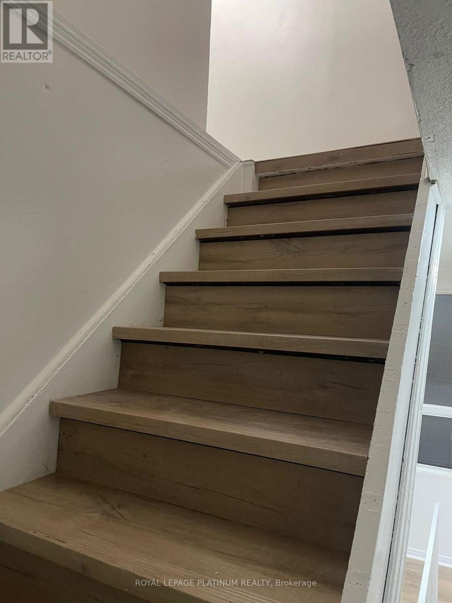 A set of wooden stairs with a white wall on the side.