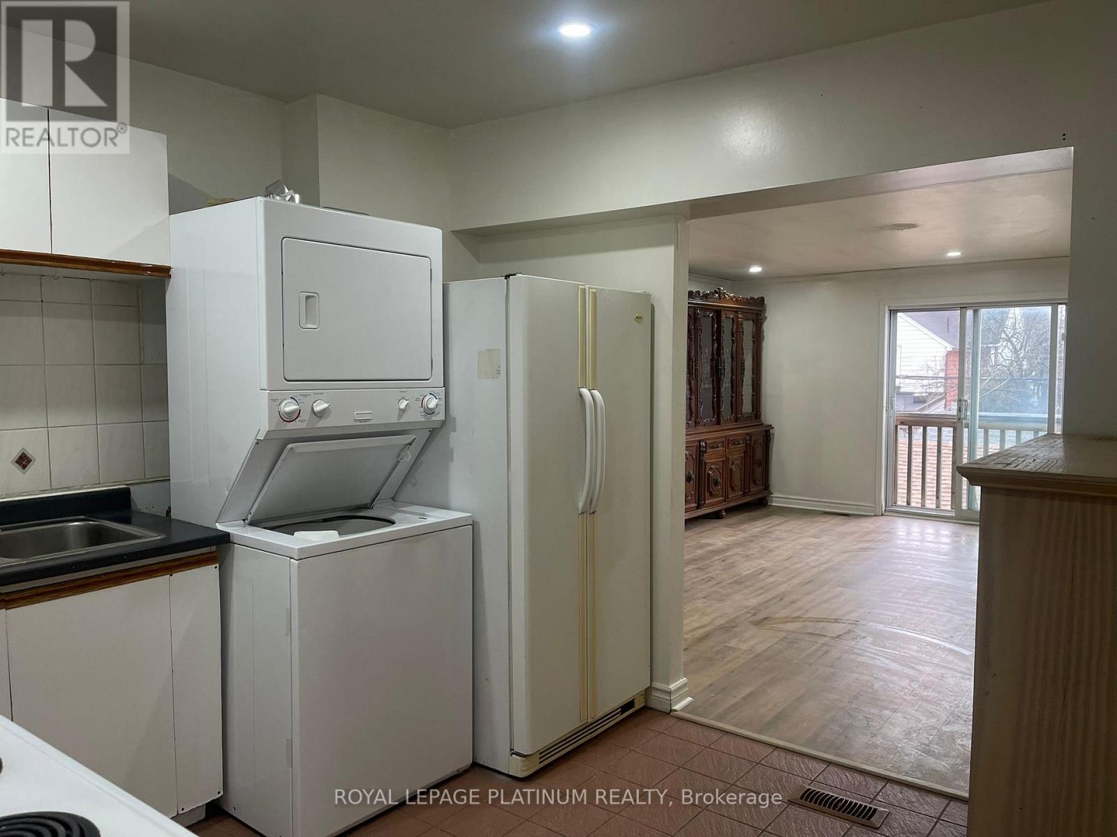 A kitchen with white appliances and wooden floors.