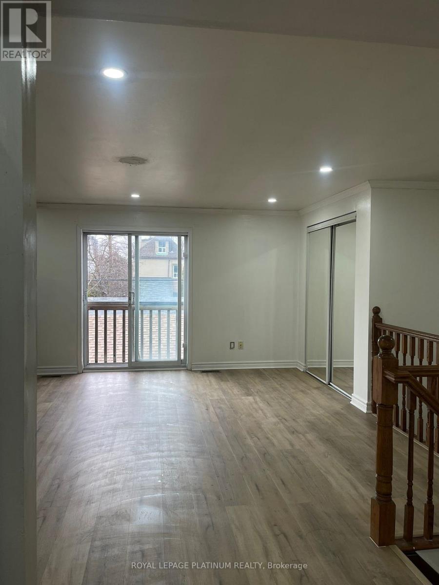 A spacious room with wooden flooring and a balcony with a railing.