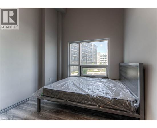 A bedroom with a bed, a window, and a view of a building outside.
