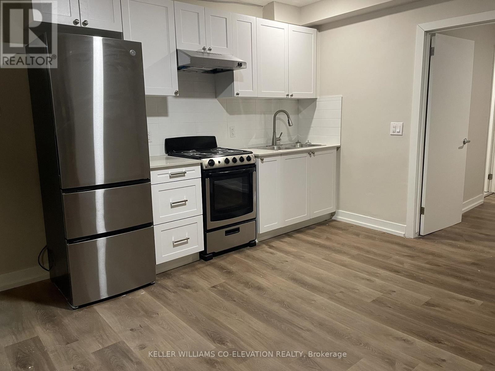 A kitchen with a stainless steel refrigerator, oven, and cabinets.