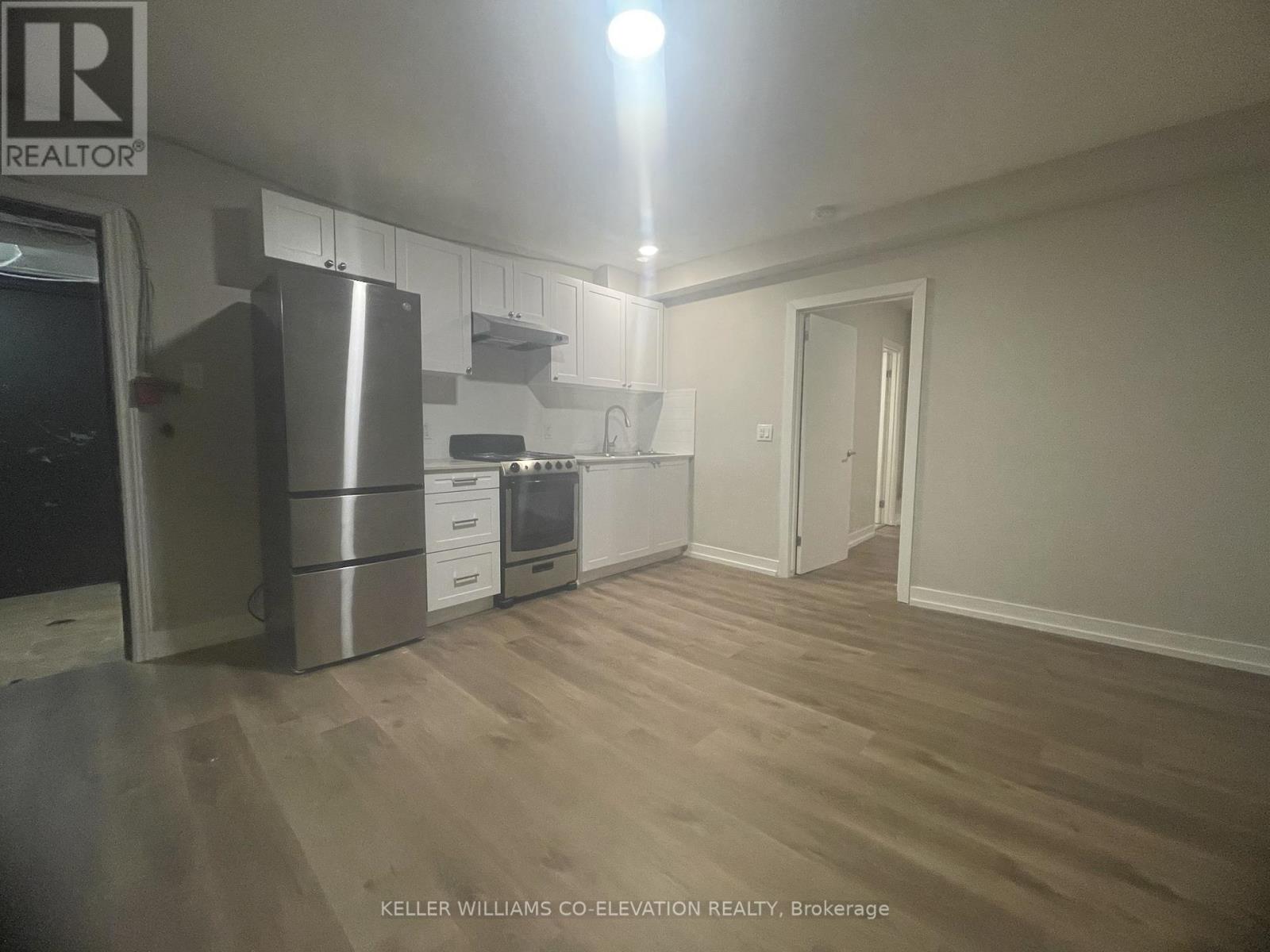 A kitchen with a refrigerator, oven, and cabinets.