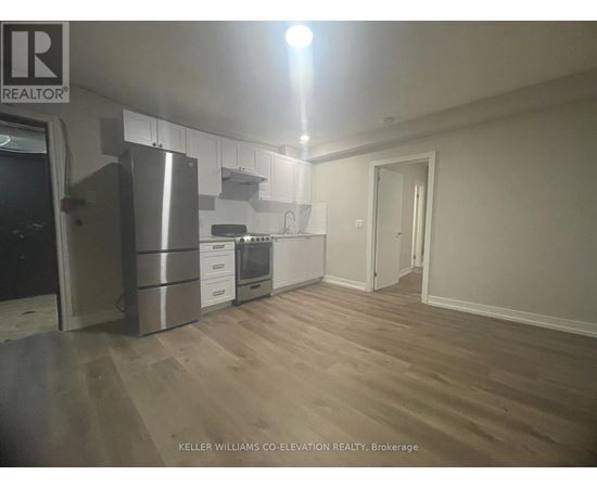 A kitchen with a refrigerator, oven, and cabinets.