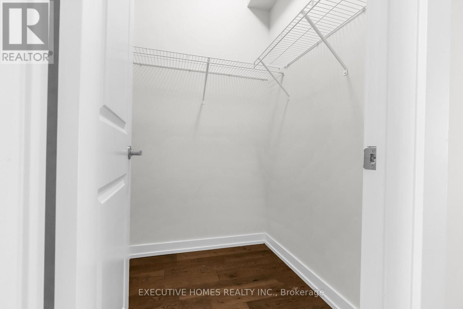A spacious room with wooden flooring and a window on the right side.