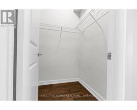 A spacious room with wooden flooring and a window on the right side.