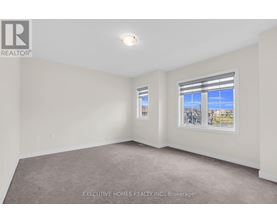 A room with a carpet floor and a window showing a view of buildings outside.